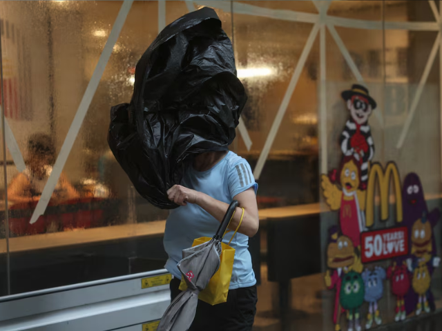 A woman braves strong winds as Typhoon Wipha approaches, in Hong Kong, China, July 20, 2025. REUTERS/Tyrone Siu