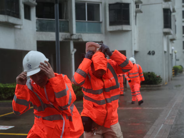 Workers brave strong winds as Typhoon Wipha approaches, in Hong Kong, China, July 20, 2025. REUTERS/Tyrone Siu