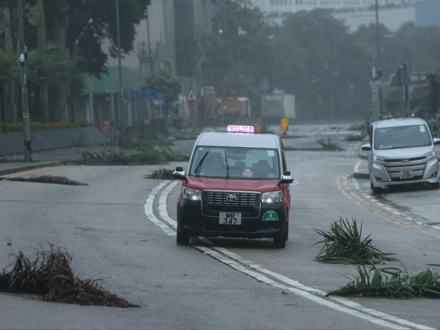 A taxi drives past debris as Typhoon Wipha approaches, in Hong Kong, China, July 20, 2025. REUTERS/Tyrone Siu