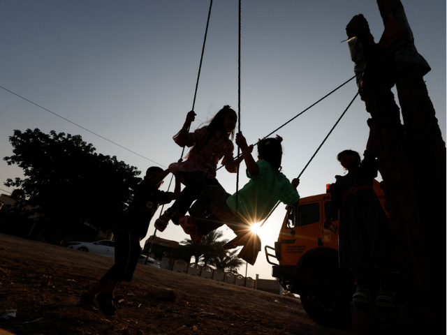 Iraqi children ride a swing on the day they celebrate Eid al-Adha, in Babylon