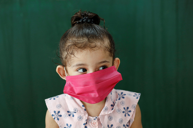 4-year-old Hamima wears a protective face mask as she waits with her family for a train at a railway station, as the outbreak of the coronavirus disease (COVID-19) continues, in Karachi, Pakistan. PHOTO: Reuters