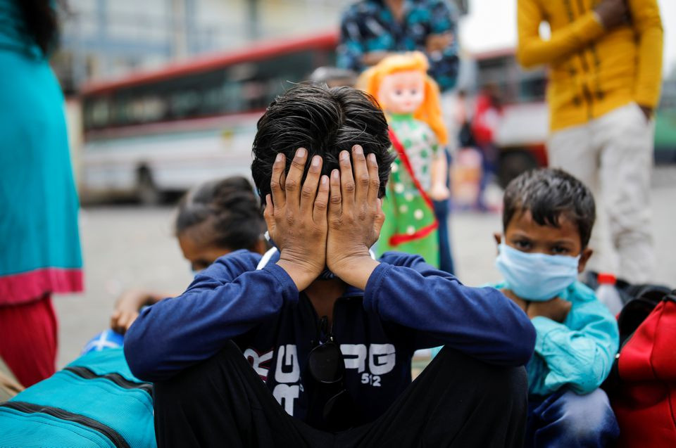 children of migrant workers sit at a bus station as they wait to board a bus to return to their villages after delhi government ordered a six day lockdown to limit the spread of the coronavirus disease covid 19 in ghaziabad on the outskirts of new delhi india april 20 2021 photo reuters