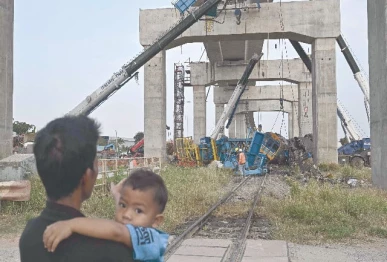 a child looks on as recovery workers stand next to the wreckage of a train that crashed when a construction crane collapsed in thailand s nakhon ratchasima province photo afp