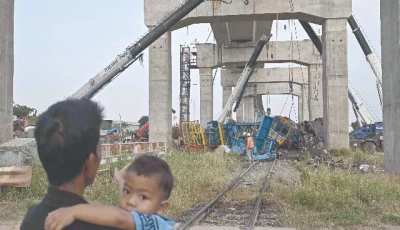 a child looks on as recovery workers stand next to the wreckage of a train that crashed when a construction crane collapsed in thailand s nakhon ratchasima province photo afp