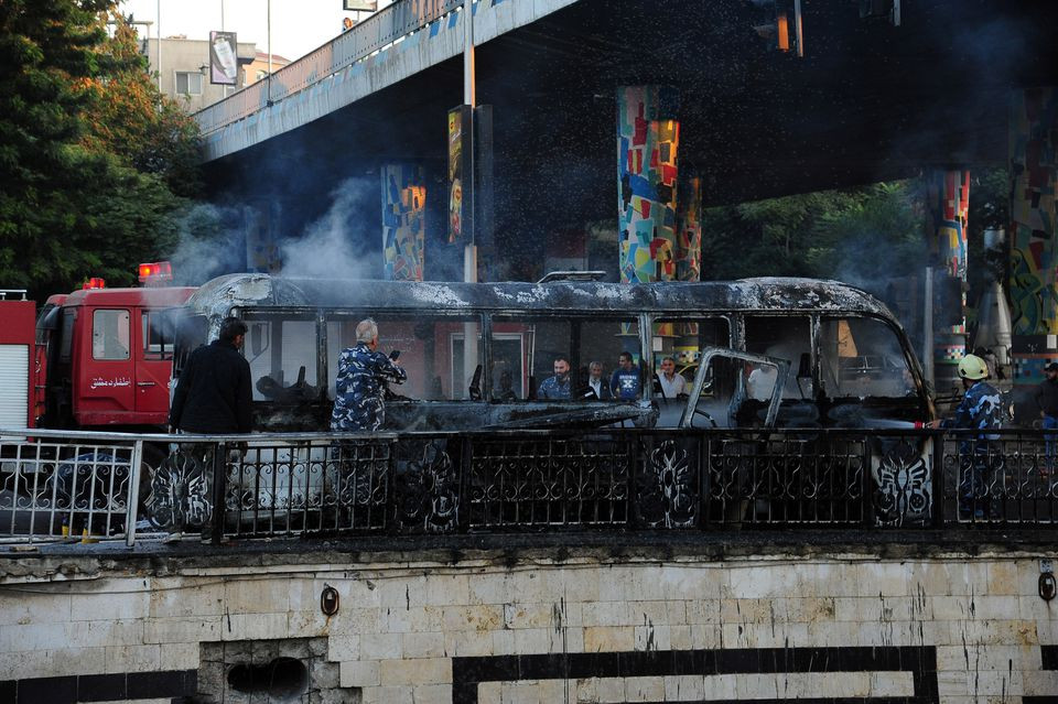 civil defense members put out a bus fire at the site of a roadside bomb attack in central damascus syria in this handout released by sana october 20 2021 photo reuters