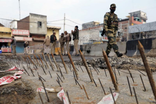 a security personnel walks past metal spikes on the ground installed by the delhi police as a security measure at tikri border where farmers are protesting against farm laws in new delhi india february 4 2021 reuters