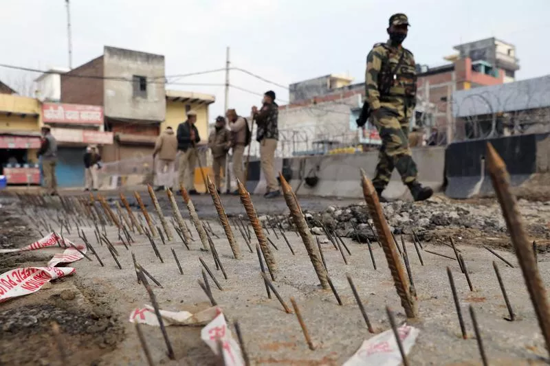 a security personnel walks past metal spikes on the ground installed by the delhi police as a security measure at tikri border where farmers are protesting against farm laws in new delhi india february 4 2021 reuters