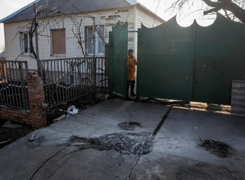 A local resident stands near her home as shell craters are seen after yesterday's shelling near the front line near the city of Novoluhanske in the Donetsk region, Ukraine, February 22. REUTERS