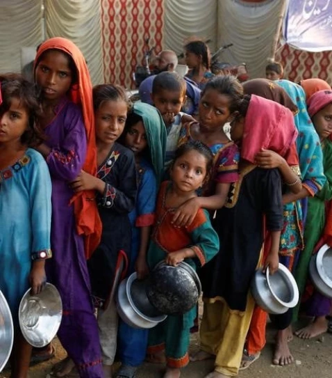 flood victims gather to receive food handouts in a camp following rains and floods during the monsoon season in sehwan pakistan september 14 2022 reuters akhtar soomro