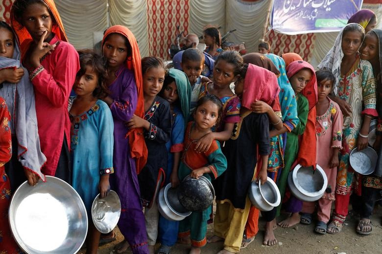 flood victims gather to receive food handouts in a camp following rains and floods during the monsoon season in sehwan pakistan september 14 2022 reuters akhtar soomro