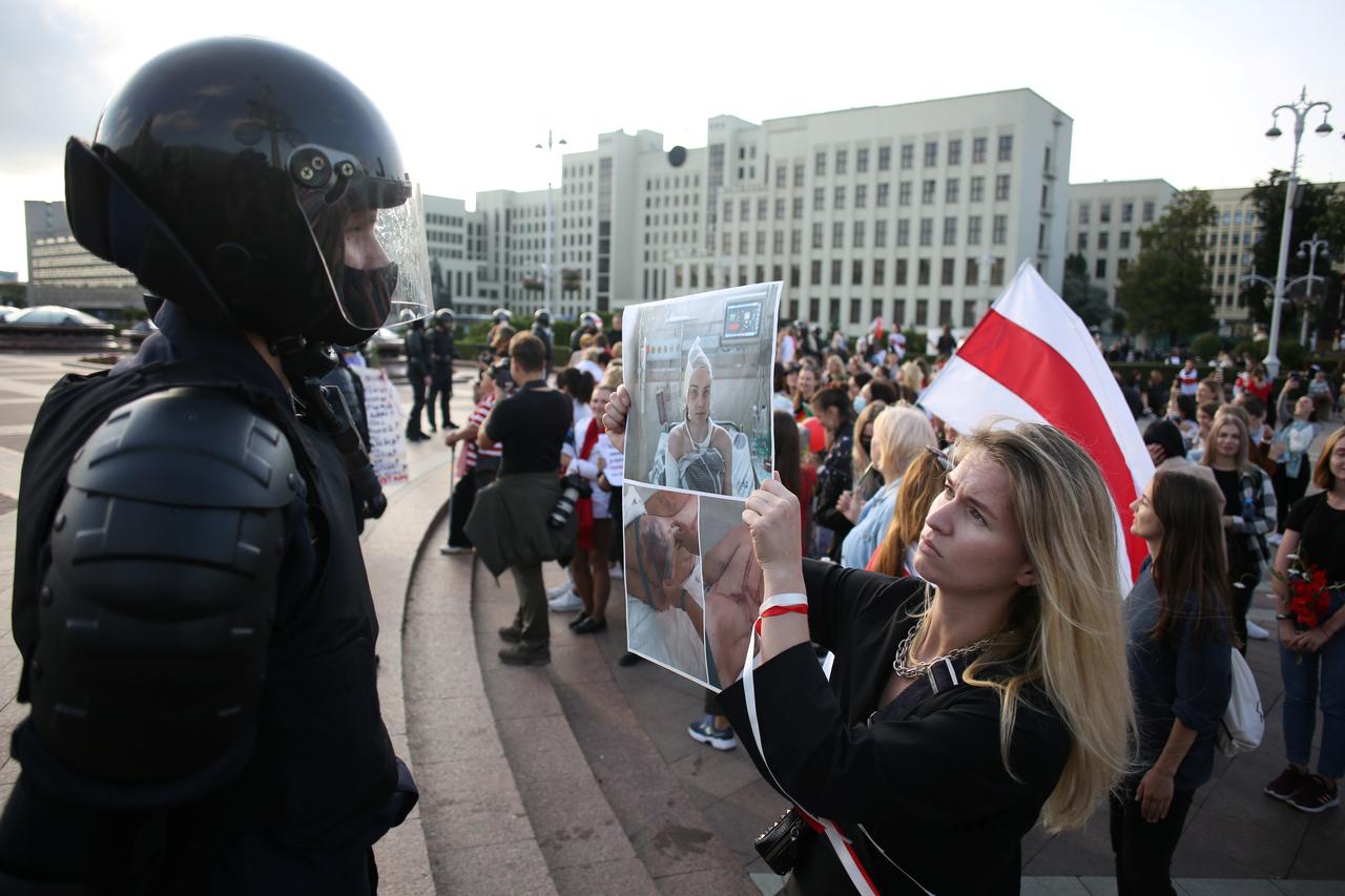 a woman holds a poster with pictures of injured persons in front of a law enforcement officer during a rally against police brutality following protests to reject the presidential election results in minsk belarus september 5 2020 reuters