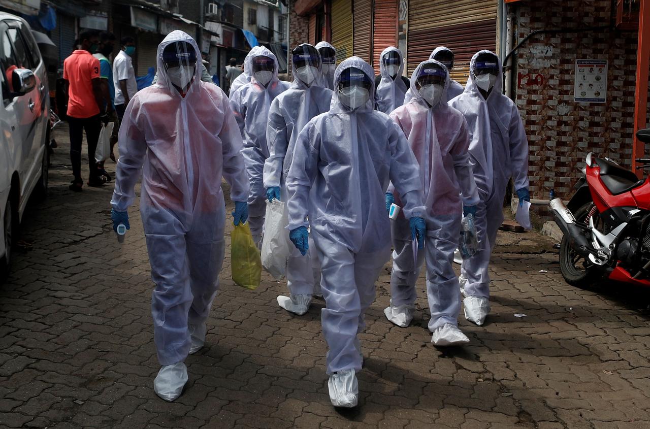 healthcare workers wearing personal protective equipment ppe walk towards different localities before the start of a check up camp for the coronavirus disease covid 19 in mumbai india reuters