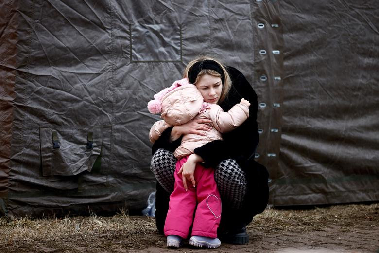 A woman fleeing the Russian invasion hugs a child at a temporary camp in Przemysl, Poland, February 28. REUTERS
