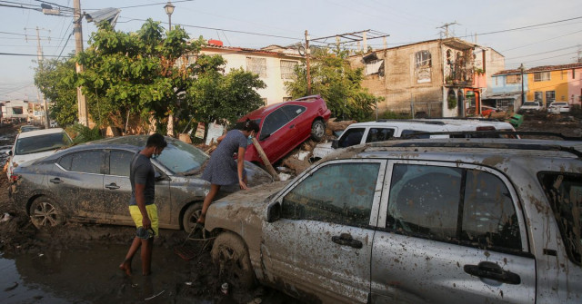 a woman climbs over a car stuck in the mud in the aftermath of hurricane otis in acapulco mexico october 29 2023 photo reuters