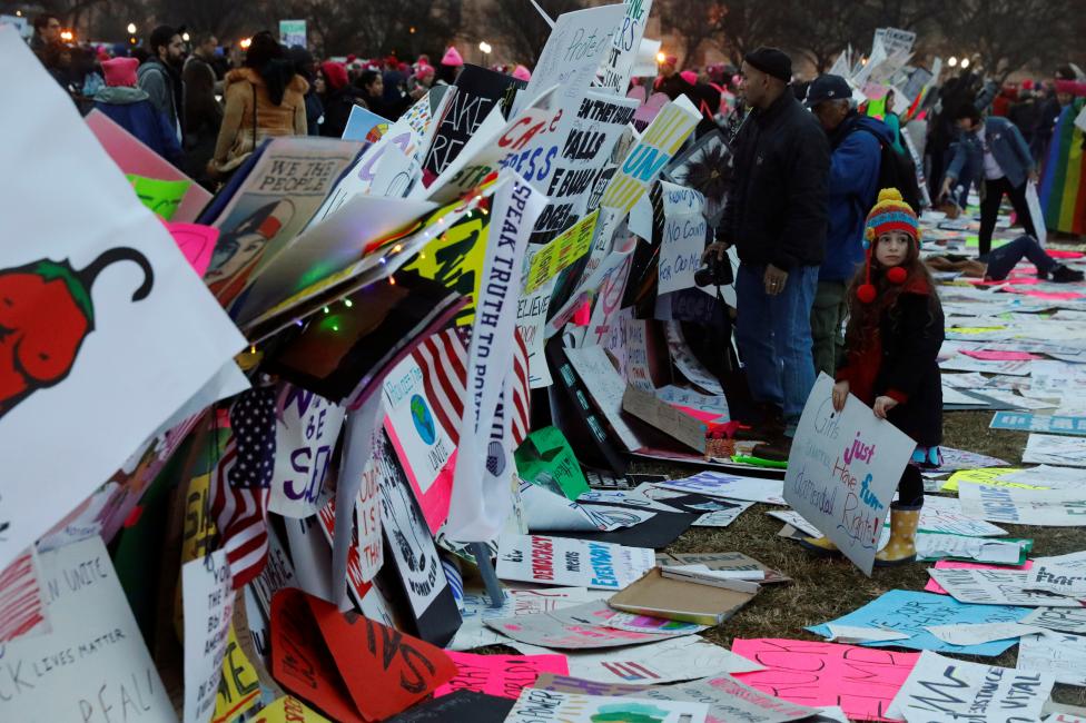 A young girl uses protest signs to build a wall while taking part in the Women's March. REUTERS/Lucas Jackson