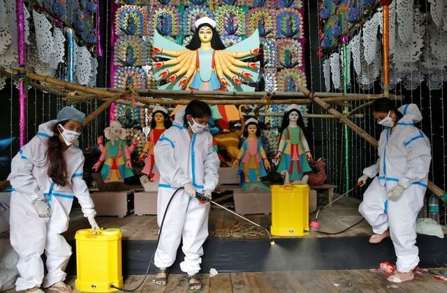 women wearing personal protective equipment ppe sanitize a pandal or a temporary platform ahead of durga puja festival amidst the spread of the coronavirus disease covid 19 in kolkata india reuters