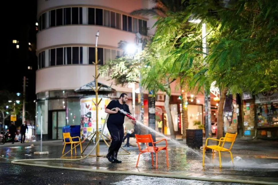 a man sprays water to clean chairs and a street as israel imposes a third national lockdown to fight climbing coronavirus disease covid 19 infections in tel aviv israel december 27 2020 reuters a man sprays water to clean chairs and a street as israel imposes a third national lockdown to fight climbing coronavirus disease covid 19 infections in tel aviv israel december 27 2020 reuters