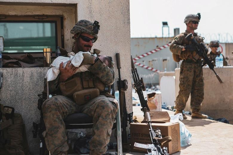 a u s marine assigned to the 24th marine expeditionary unit meu holds a baby during an evacuation at hamid karzai international airport kabul afghanistan august 20 2021 sgt isaiah campbell u s marine corps handout via reuters