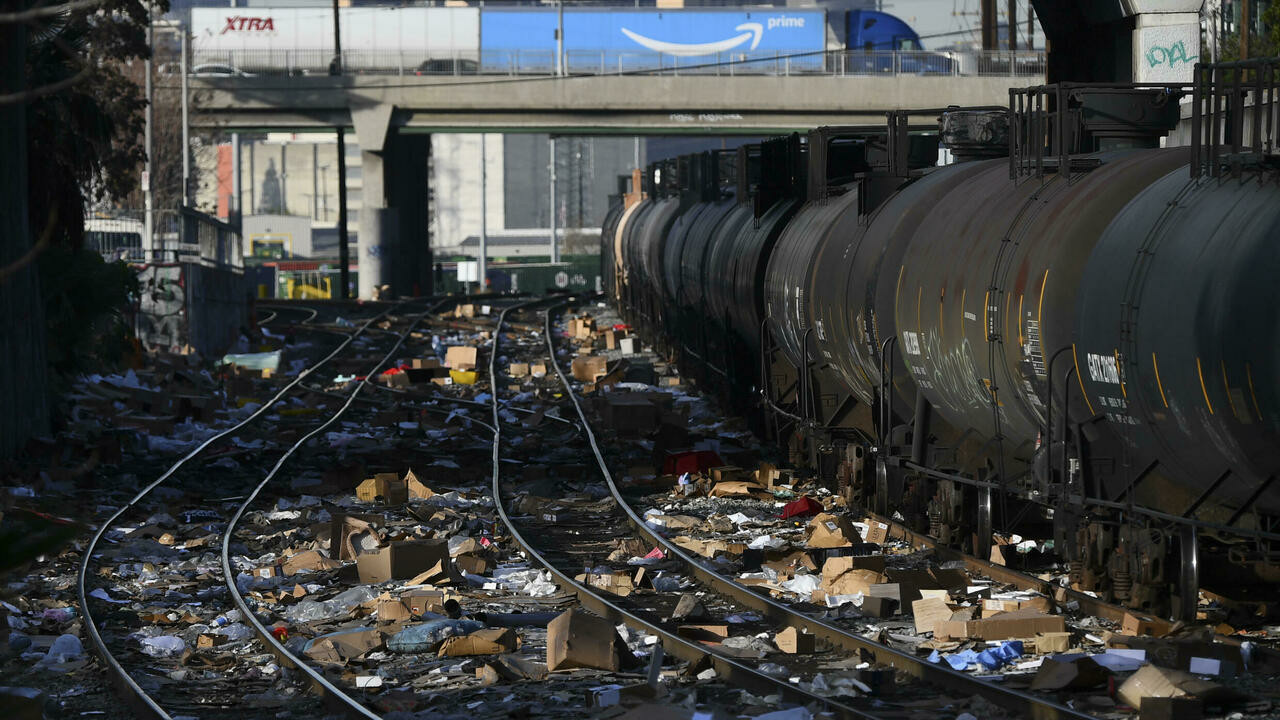 a train carrying shipping containers passes through a section of union pacific train tracks littered with thousands of opened boxes and packages stolen from cargo shipping containers on january 14 2022 afp