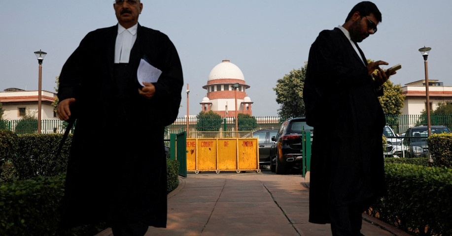 a lawyer looks into his mobile phone as another walks past in front of india s supreme court in new delhi december 11 2023 reuters adnan abidi