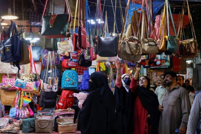 people look at handbags on display outside shops in a market ahead of eidul fitr celebrations in karachi photo reuters people look at handbags on display outside shops in a market ahead of eidul fitr celebrations in karachi photo reuters