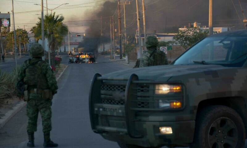 mexicans soldiers stand guard near burning vehicles on a street during an operation to arrest the son of joaquin el chapo guzman ovidio guzman in culiacan sinaloa state mexico on january 5 photo afp