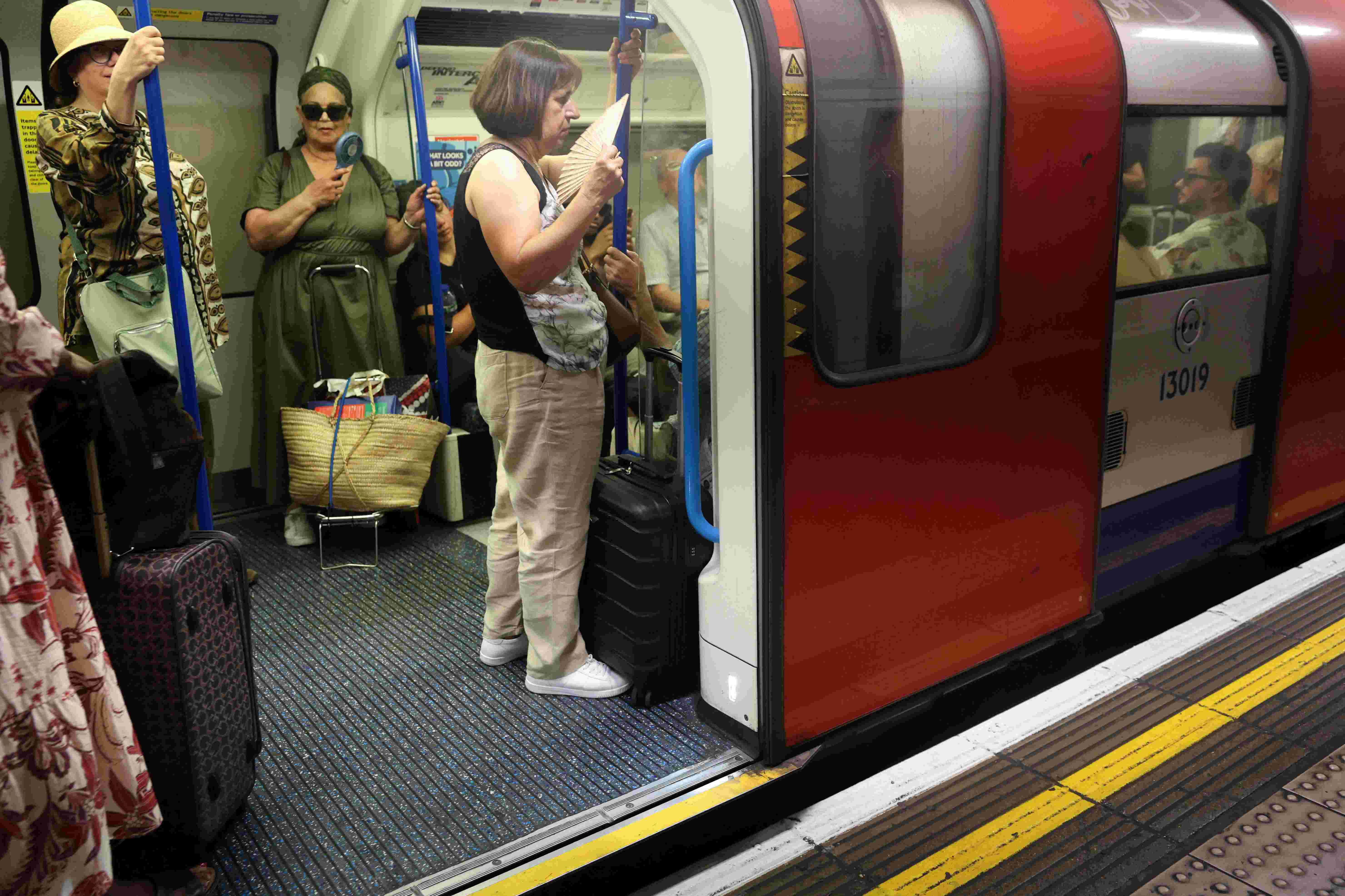 A person uses a portable fan on an underground train in central London on June 24, 2026. The UK's meteorological office has issued an extremely rare red heat warning -- only issued once before -- for June24 and 25, as temperatures could soar to 40C, unprecedented for the time of the year. Photo: AFP