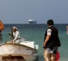 armed men stand on the beach as the galaxy leader commercial ship seized by yemen s houthis last month is anchored off the coast of al salif yemen december 5 2023 reuters khaled abdullah file photo
