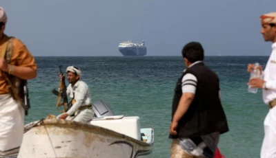 armed men stand on the beach as the galaxy leader commercial ship seized by yemen s houthis last month is anchored off the coast of al salif yemen december 5 2023 reuters khaled abdullah file photo
