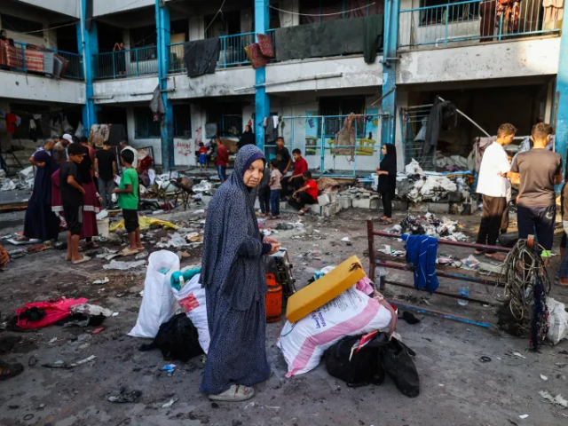 Palestinians salvage items after an Israeli strike on a tent camp at the UNRWA-run Abou Helou school for girls at the Bureij refugee camp [Eyad Baba/AFP]