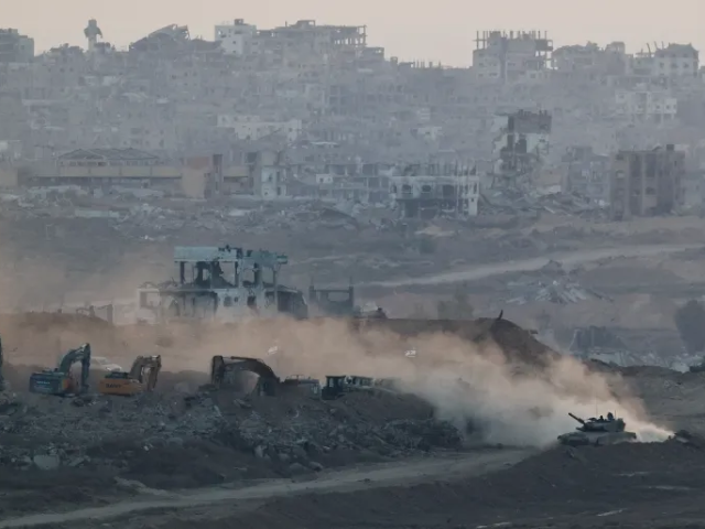 An Israeli tank manoeuvres near heavy machinery with the destruction of northern Gaza evident in the background [Amir Cohen/Reuters]
