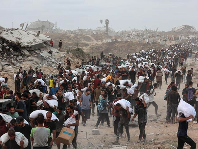 Palestinians bring back aid parcels they managed to procure as they walk on a coastal path west of Beit Lahia on July 29, 2025, after aid trucks entered the Israel-besieged Gaza Strip from the northern Zikim border crossing. — AFP