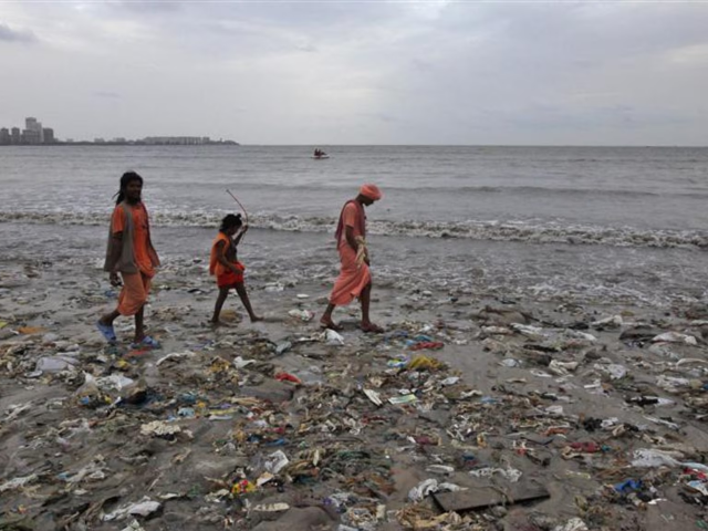 Ram Singh (L) and his relatives, dressed in traditional Hindu saffron-coloured clothes walk on a garbage-strewn beach against the backdrop of monsoon clouds on World Environment Day in Mumbai, June 5, 2012. According to the United Nations Environment Programme website, World Environment Day is celebrated annually on June 5 to raise global awareness and motivate action for environmental protection. REUTERS/Vivek Prakash