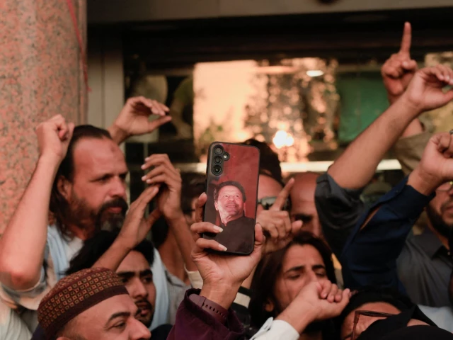 a supporter of jailed former prime minister imran khan s pakistan tehreek e insaf pti party holds a mobile phone with a photo of khan during a protest over concerns about their leader s health in karachi pakistan november 28 2025 reuters