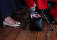 a u s flag sticks out from the purse of a citizen candidate attending a u s citizenship and immigration services uscis naturalization ceremony aboard the 1885 tall ship wavertree at the south street seaport in new york city u s june 14 2023 reuters