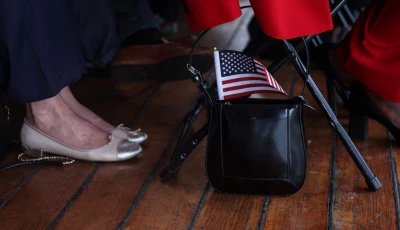 a u s flag sticks out from the purse of a citizen candidate attending a u s citizenship and immigration services uscis naturalization ceremony aboard the 1885 tall ship wavertree at the south street seaport in new york city u s june 14 2023 reuters