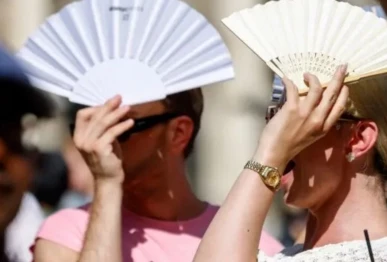 tourists protect themselves with fans against the sun at munich s marienplatz square on june 29 2025 in southern germany afp