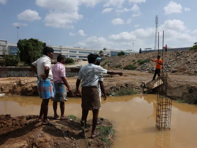 farmers speak with a security guard near the compound wall of a tata electronics components factory for apple s iphone in hosur photo reuters farmers speak with a security guard near the compound wall of a tata electronics components factory for apple s iphone in hosur photo reuters