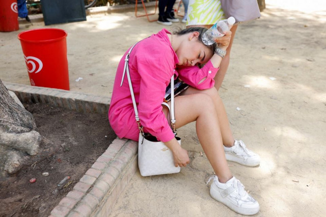 a woman cools herself with a water bottle during the first heatwave of the year in seville spain june 11 2022 photo reuters a woman cools herself with a water bottle during the first heatwave of the year in seville spain june 11 2022 photo reuters