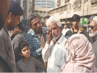a family member of a gul plaza salesman wipes away tears while standing before the charred remains of the building mourning the loss of a lifetime of work and memories in the devastating fire photo app