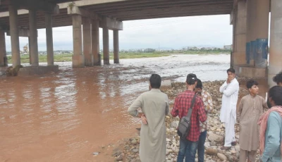 locals gather under the soan bridge on wednesday anxiously awaiting recovery of a car swept away a day earlier by the devastating floodwaters that inundated parts of the twin cities photo online