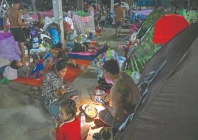a displaced family uses a flashlight as they eat a meal at a temporary camp along the cambodia thailand border photo afp