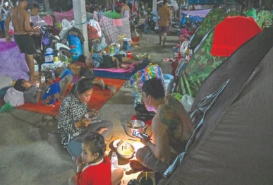 a displaced family uses a flashlight as they eat a meal at a temporary camp along the cambodia thailand border photo afp