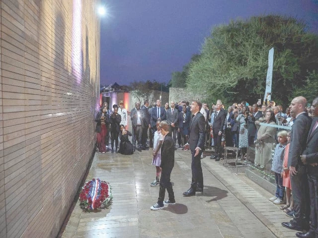 france s president emmanuel macron looks at a lit wall with names of french individuals who fought against apartheid during a commemoration ceremony attended by south africa s deputy president paul mashatile in pretoria photo afp