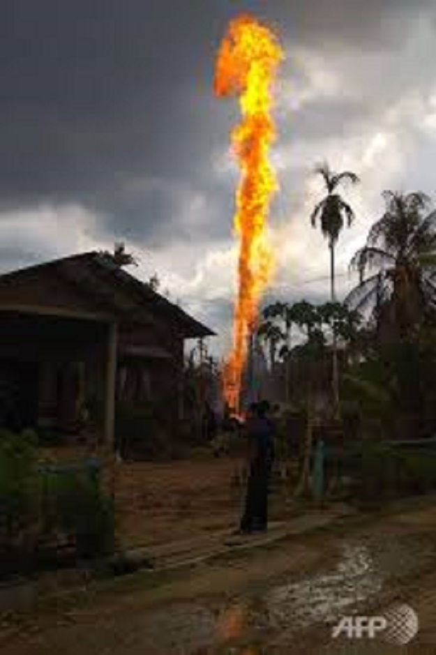 People watch as a fire burns at an oil well in Peureulak, Indonesia's Aceh province, on April 25, 2018. PHOTO: AFP