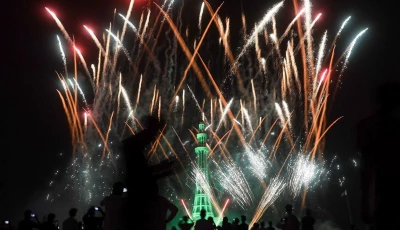 people watch fireworks exploding over the illuminated minar e pakistan monument during the celebration of independence day in lahore on august 14 2025 photo reuters