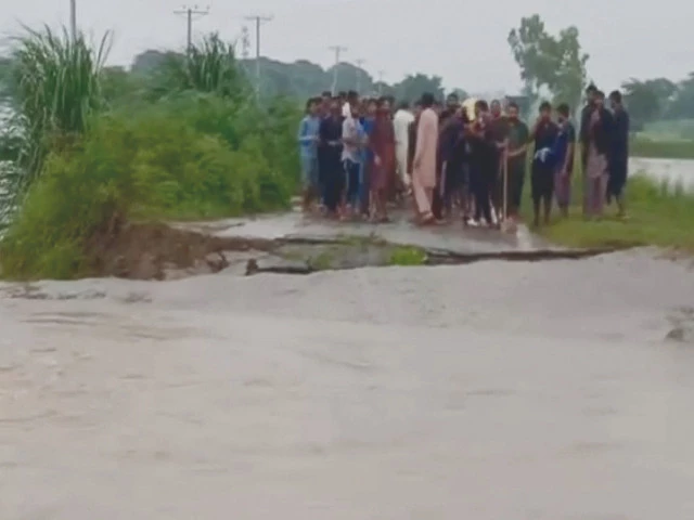 people stand near a damaged road in a flooded area of narowal district photo nni