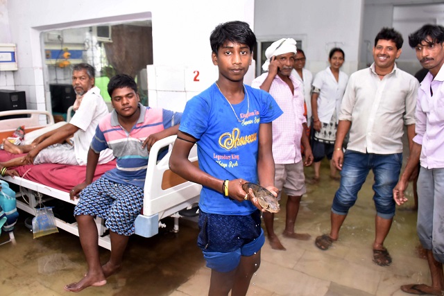 This picture shows a relative's patient holding a fish after he caught it inside a waterlogged hospital ward. PHOTO: AFP