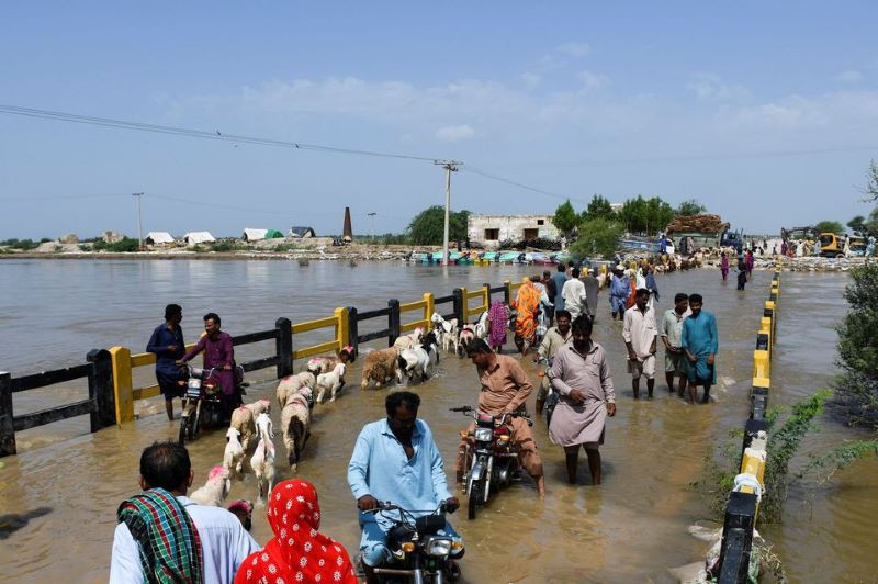 people cross a bridge amid flood waters following rains and floods during the monsoon season in puran dhoro badin pakistan august 30 2022 reuters