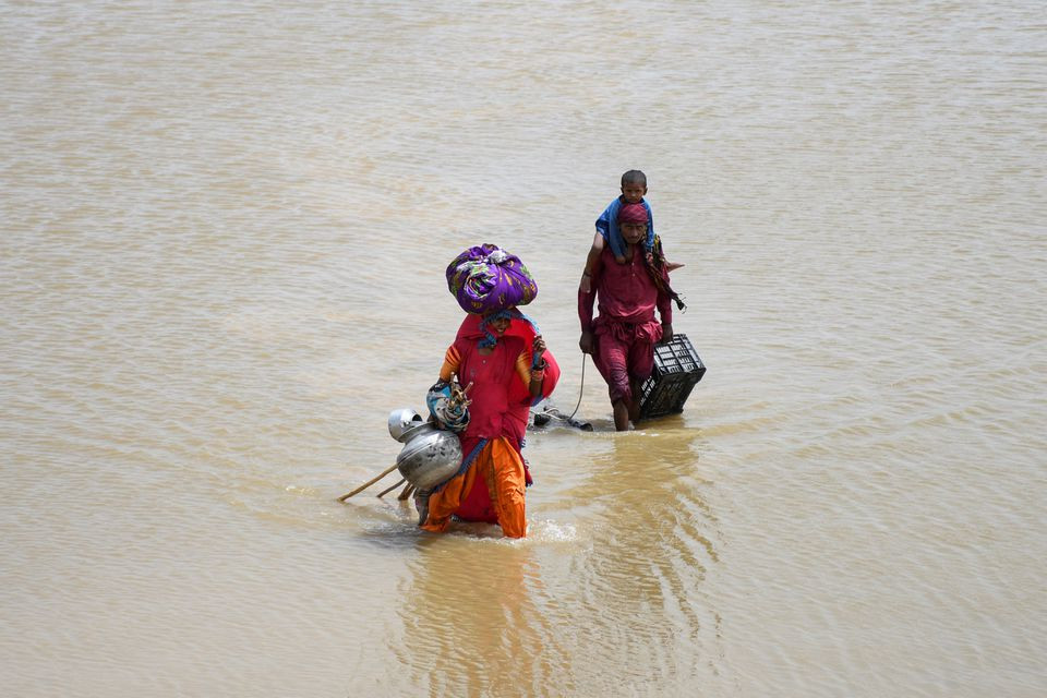 a family with their belongings wade through rain waters following rains and floods during the monsoon season in jamshoro pakistan august 26 2022 photo reuters